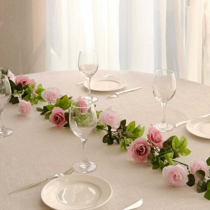 Table setting with glasses, plates, and artificial rose garland decoration.