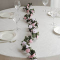 Floral table runner with pink and white roses on a dining table.