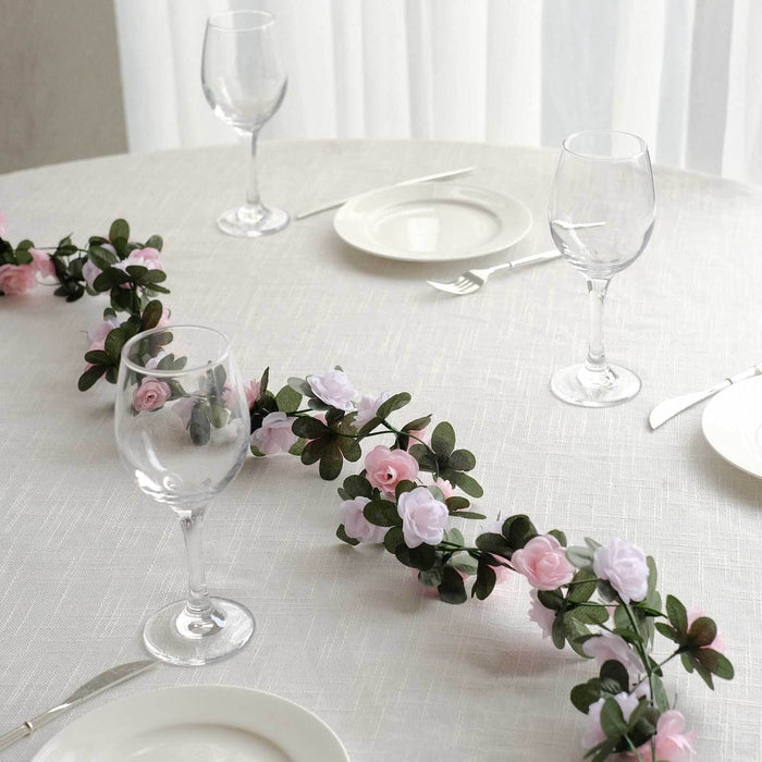 Floral table centerpiece with pink and white roses and greenery.