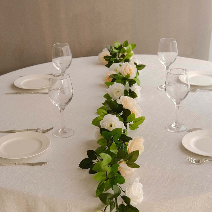 Elegant table setting with white roses and greenery on a round table.