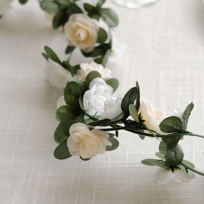 Artificial flower garland with white and cream blooms on a light textured background.