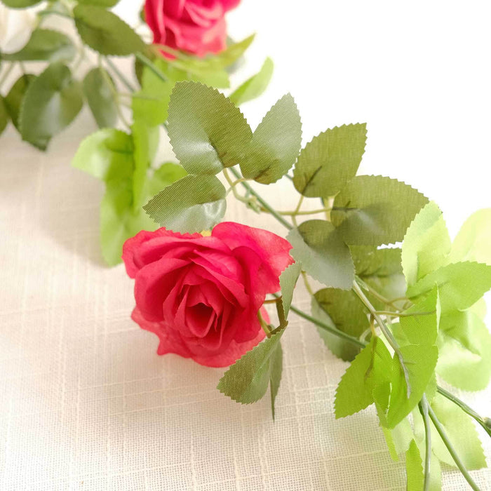Artificial pink rose garland with green leaves on a soft background.