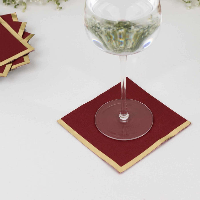 Burgundy drink coasters with gold trim for elegant table settings.