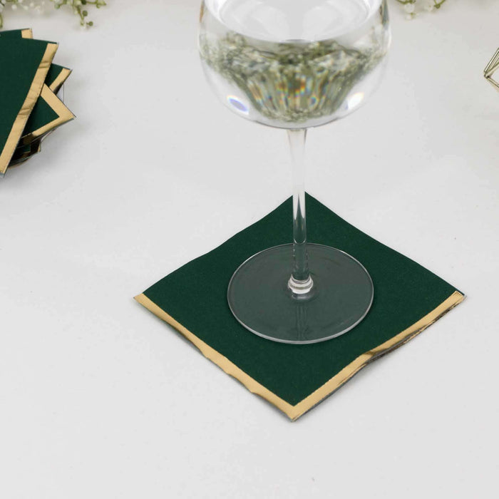 Green coasters with gold trim under a glass on a table.