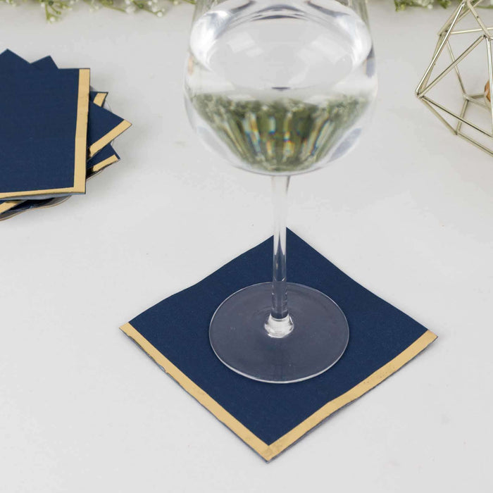 Navy blue coasters with gold edges under a glass of water