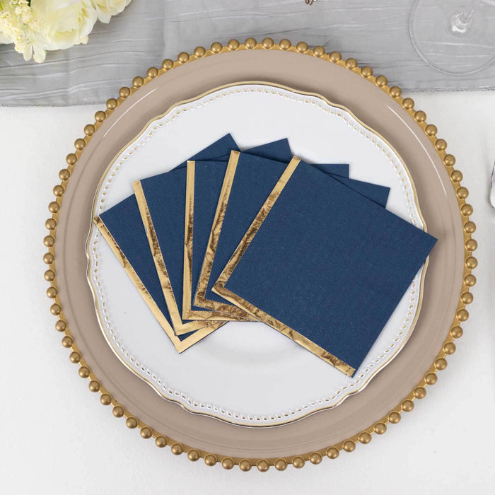 Navy blue napkins with gold trim on a decorative plate