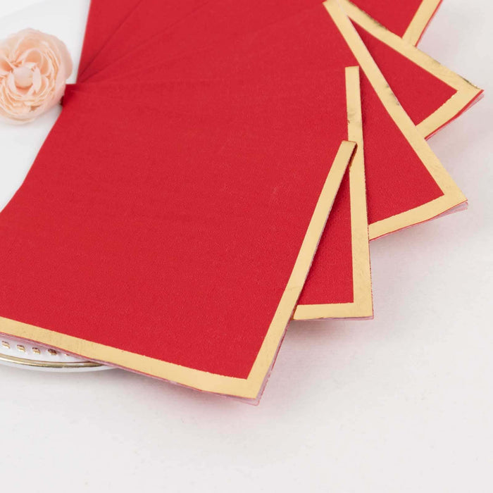Red napkins with gold borders on a white plate.