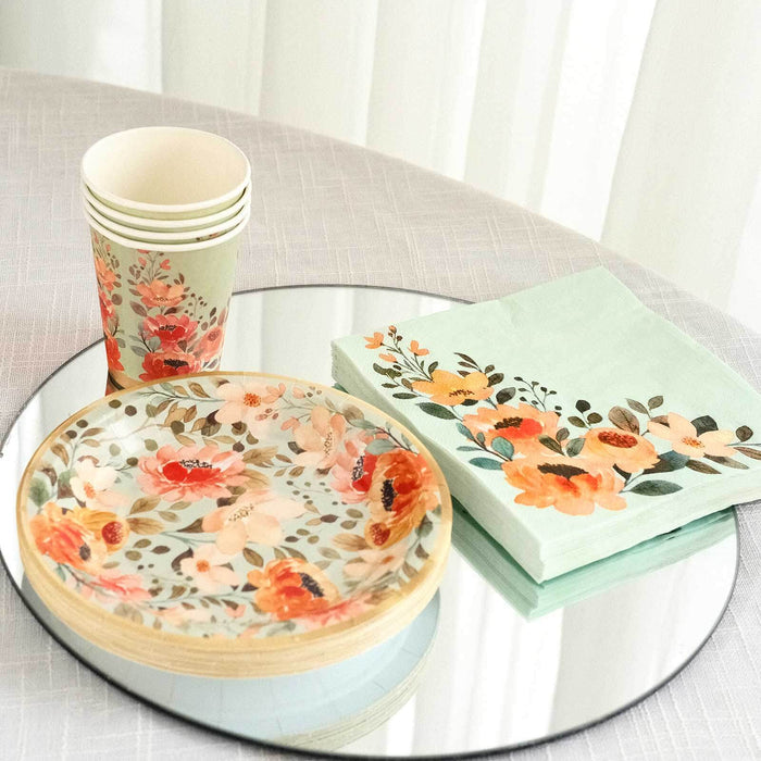 Floral paper plates, cups, and napkins arranged on a mirrored surface.