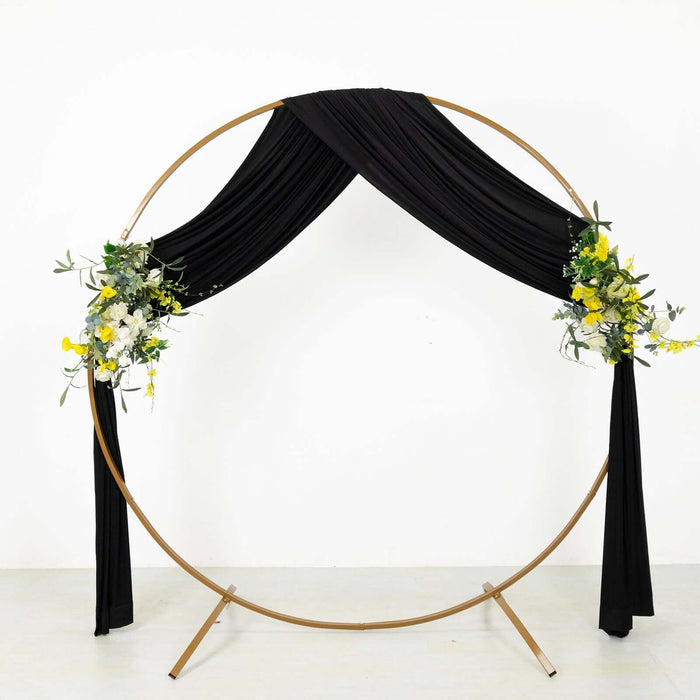 Gold circular wedding arch with black drapery and floral accents