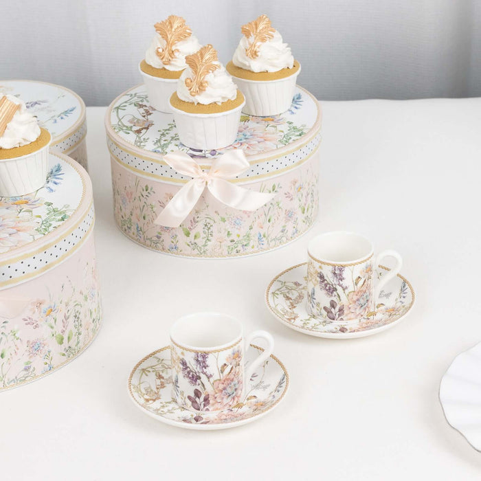 Elegant floral tea set with matching saucers and decorative cupcake boxes.
