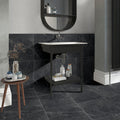 Bathroom with black marble effect tiles on the floor and the wall behind basin.