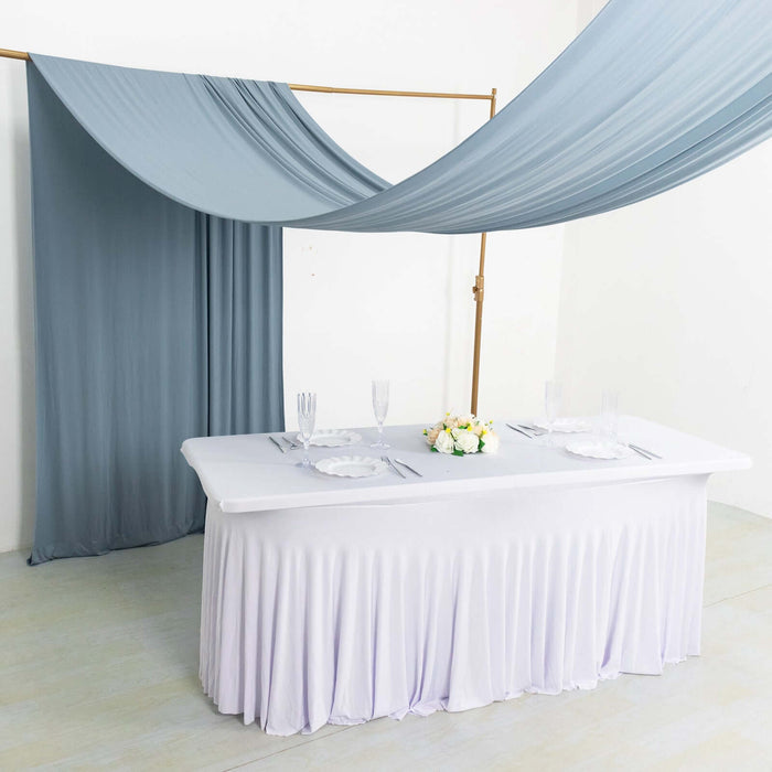 Elegant table setup with draped fabric and floral centerpiece in a minimalist setting.