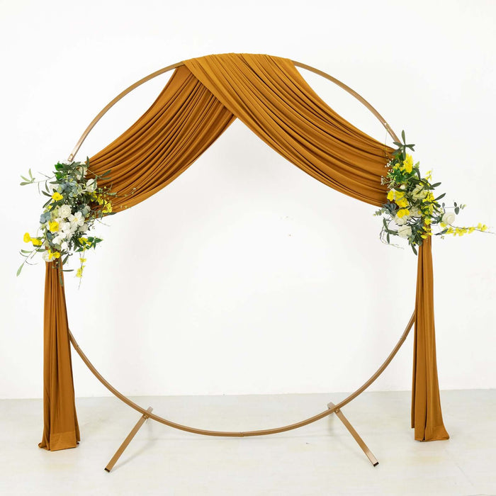 Brown draped wedding arch with floral accents on a white background