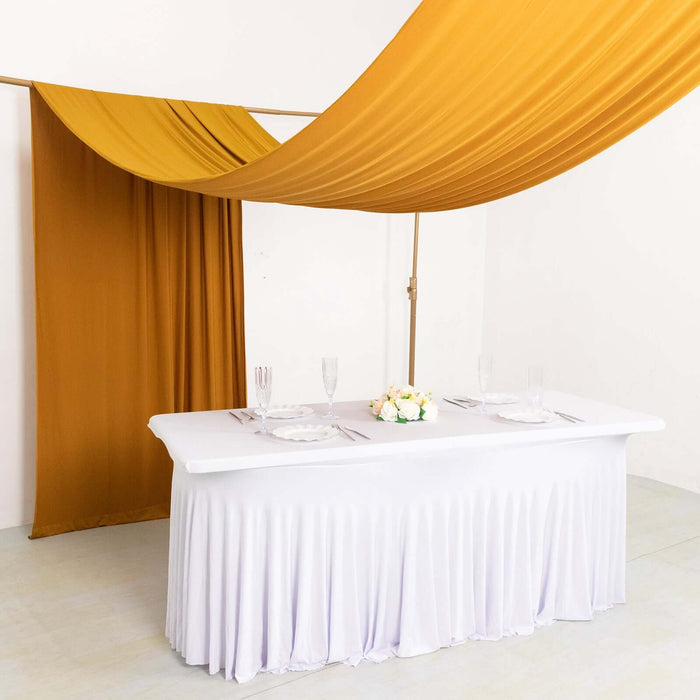 Elegant table setting with white tablecloth and golden drapes for events.