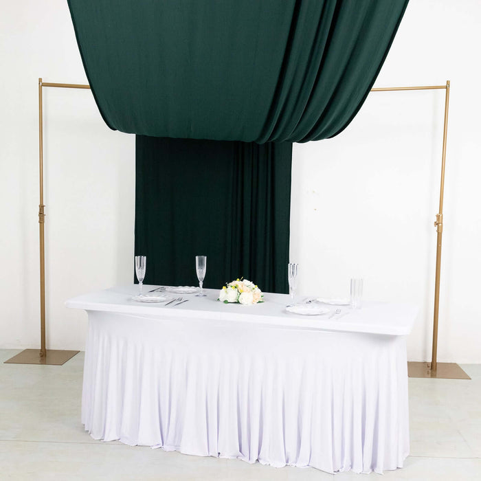 Elegant white tablecloth with gold decorations and green drapery backdrop.