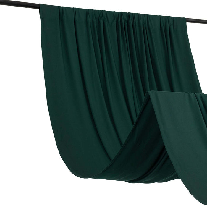 Dark green draped fabric hanging from a black rod