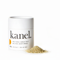 A white cylindrical container labeled 'kanel. Holy Grail Garlic Salt' next to a small pile of garlic salt.
