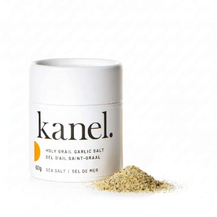 A white cylindrical container labeled 'kanel. Holy Grail Garlic Salt' next to a small pile of garlic salt.