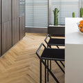 Kitchen with a wood effect herringbone luxury vinyl floor, black chairs, and a white island.