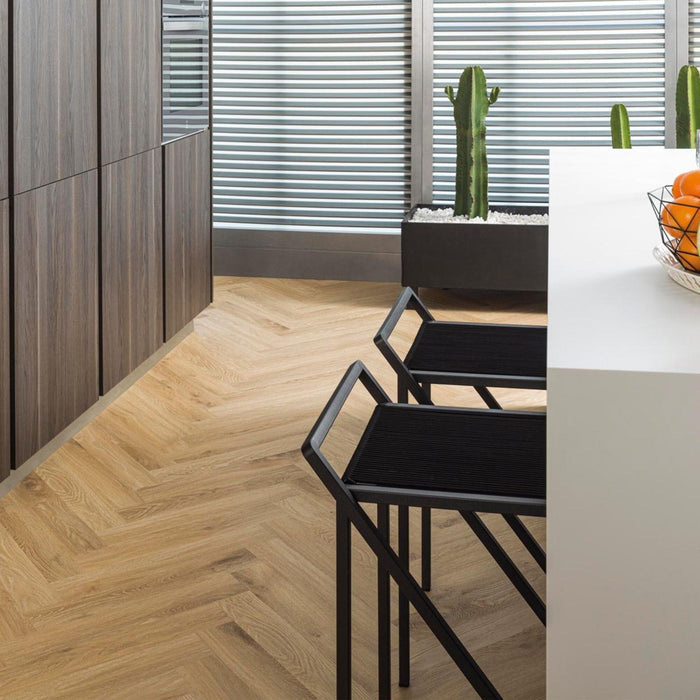 Kitchen with a wood effect herringbone luxury vinyl floor, black chairs, and a white island.