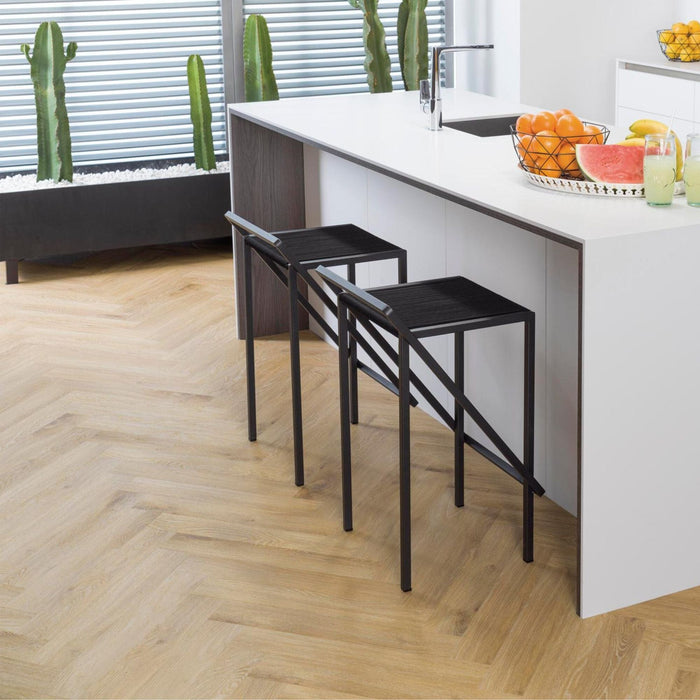 Modern kitchen with white island, black stools and wood effect herringbone luxury vinyl flooring.