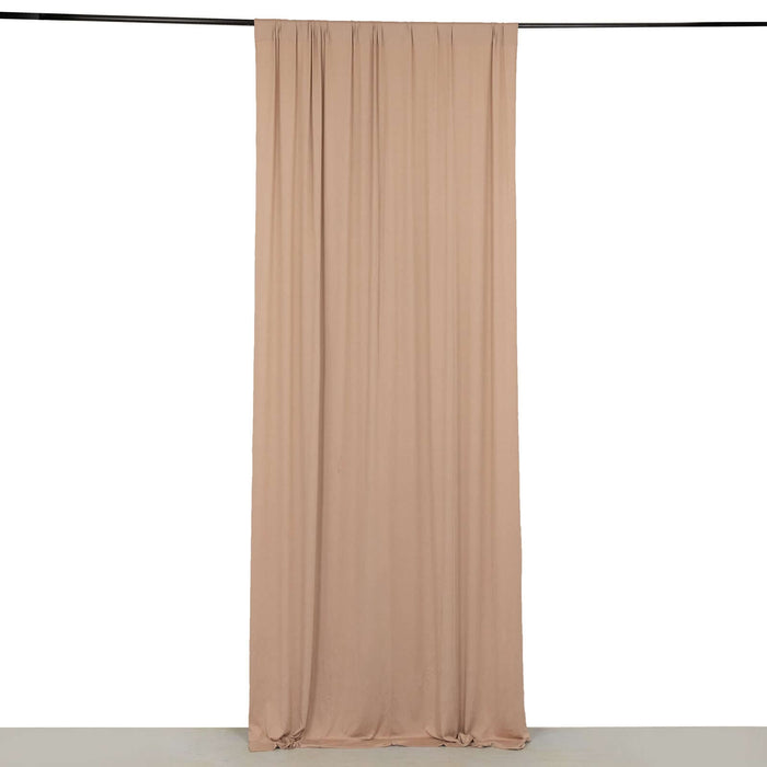 Beige fabric drapery hanging from a black rod against a plain backdrop