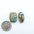Royston Turquoise cabochons, blue-green color with natural matrix, polished stones on a white background, with a US dime for scale
