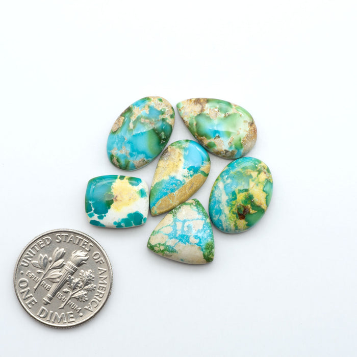 Sonoran Mountain Turquoise cabochons, blue-green color with natural matrix, polished stones on a white background, with a US dime for scale