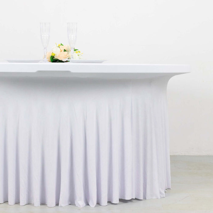 White table with pleated skirt, decorated with flowers and champagne glasses.