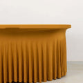 Yellow pleated tablecloth draped over a table against a plain backdrop.