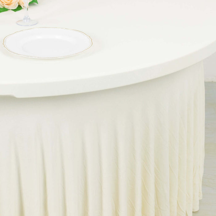 Round table with a pleated cream tablecloth and a decorative plate.
